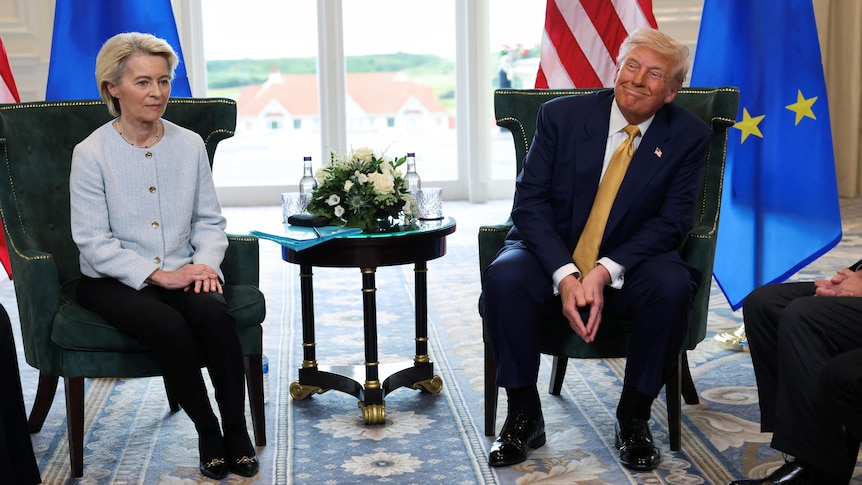 Donald Trump and Ursula von der Leyen seated during a formal diplomatic meeting, with U.S. and EU flags in the background.