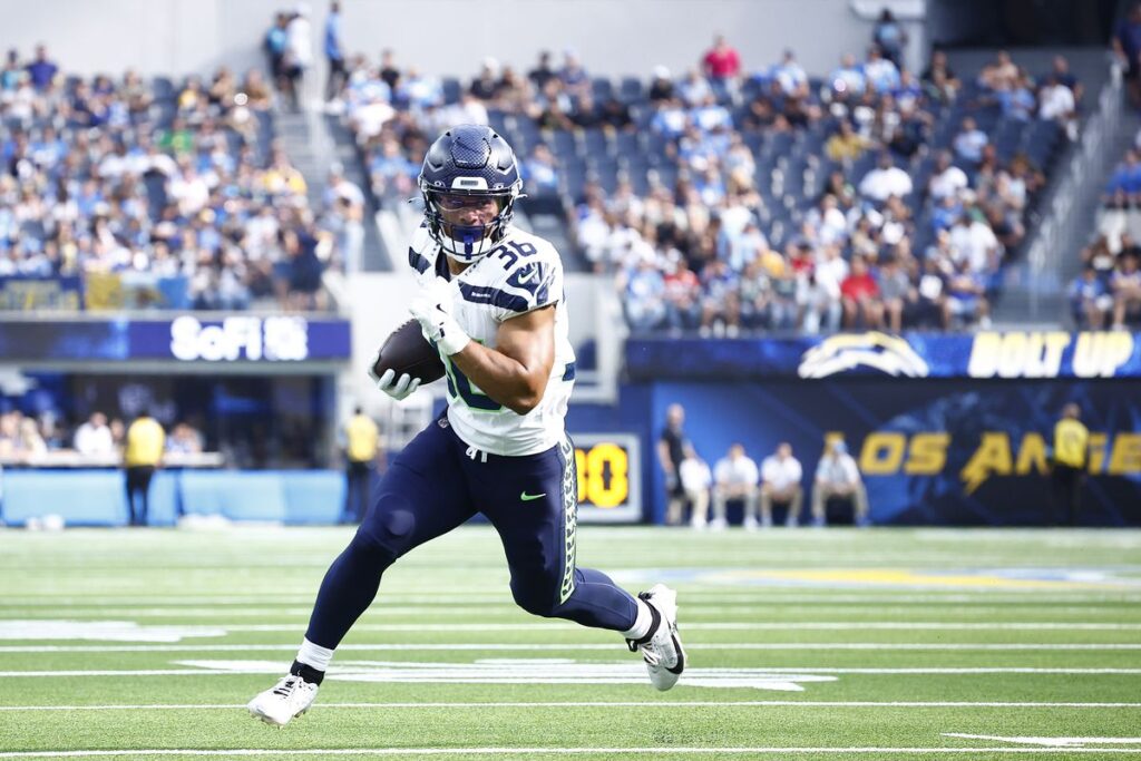 American football player George Holani running with the ball during a game.