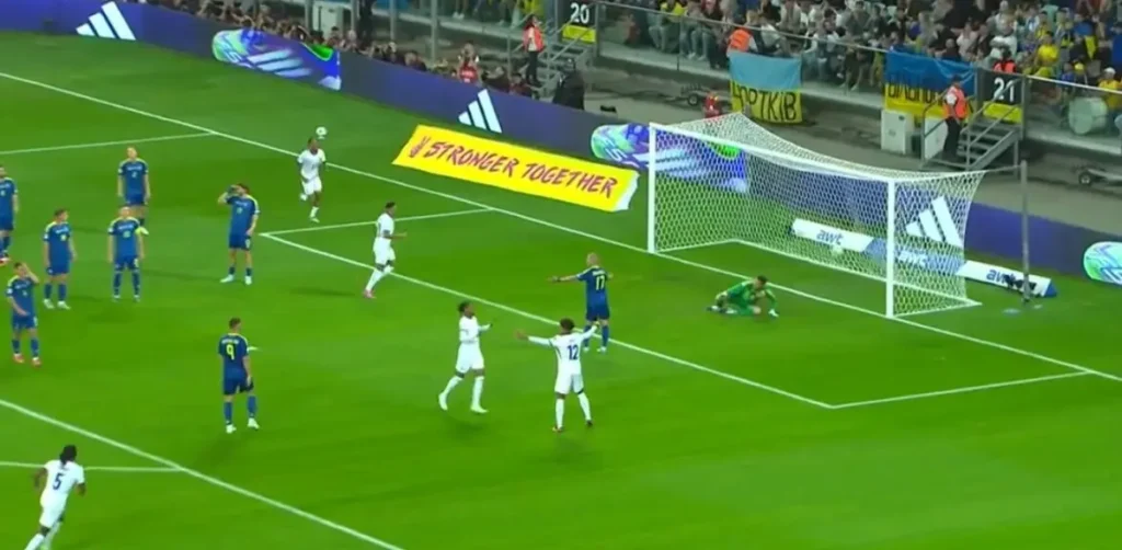 French players celebrate after scoring a goal against Ukraine during the World Cup 2026 qualifier match, with the Ukrainian goalkeeper on the ground inside the penalty area.